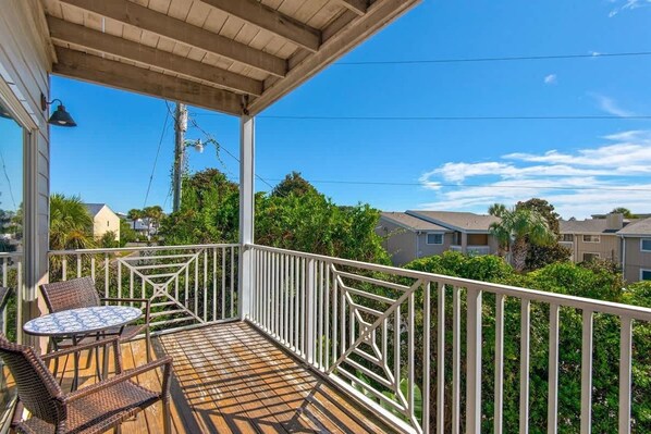 A wooden deck with a railing, a table, and chairs. - Bright 3BR Townhome Gulf Views Steps to Beach (Destin)