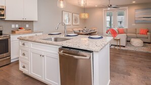 Une cuisine moderne avec des meubles blancs, des plans de travail en granit et des appareils électroménagers en acier inoxydable.