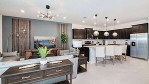 Una cucina moderna con mobili scuri, elettrodomestici in acciaio inossidabile e illuminazione a sospensione.