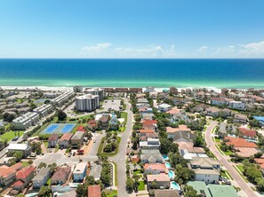 An aerial view of a coastal residential area with houses, a parking lot, and a beach in the background. - Family Paradise in Destin Pool Beach Grill (Destin)