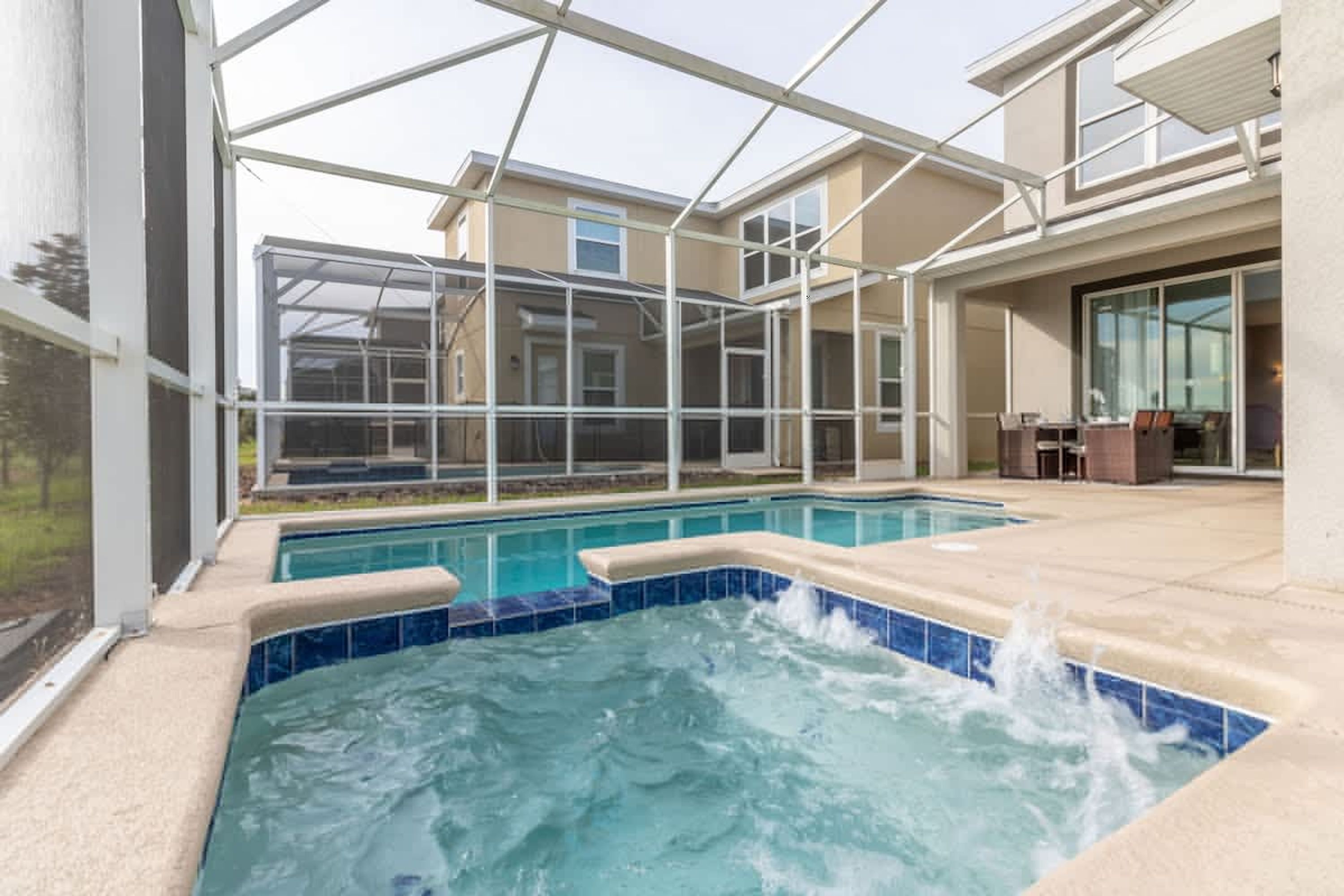 A swimming pool with a hot tub, surrounded by a covered patio area.