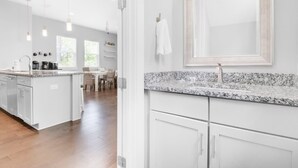 A modern kitchen with white cabinetry, granite countertops, and pendant lighting. - Cabin by the Sea - 3bdr - Pool Walk 2 Beach (Miramar Beach)