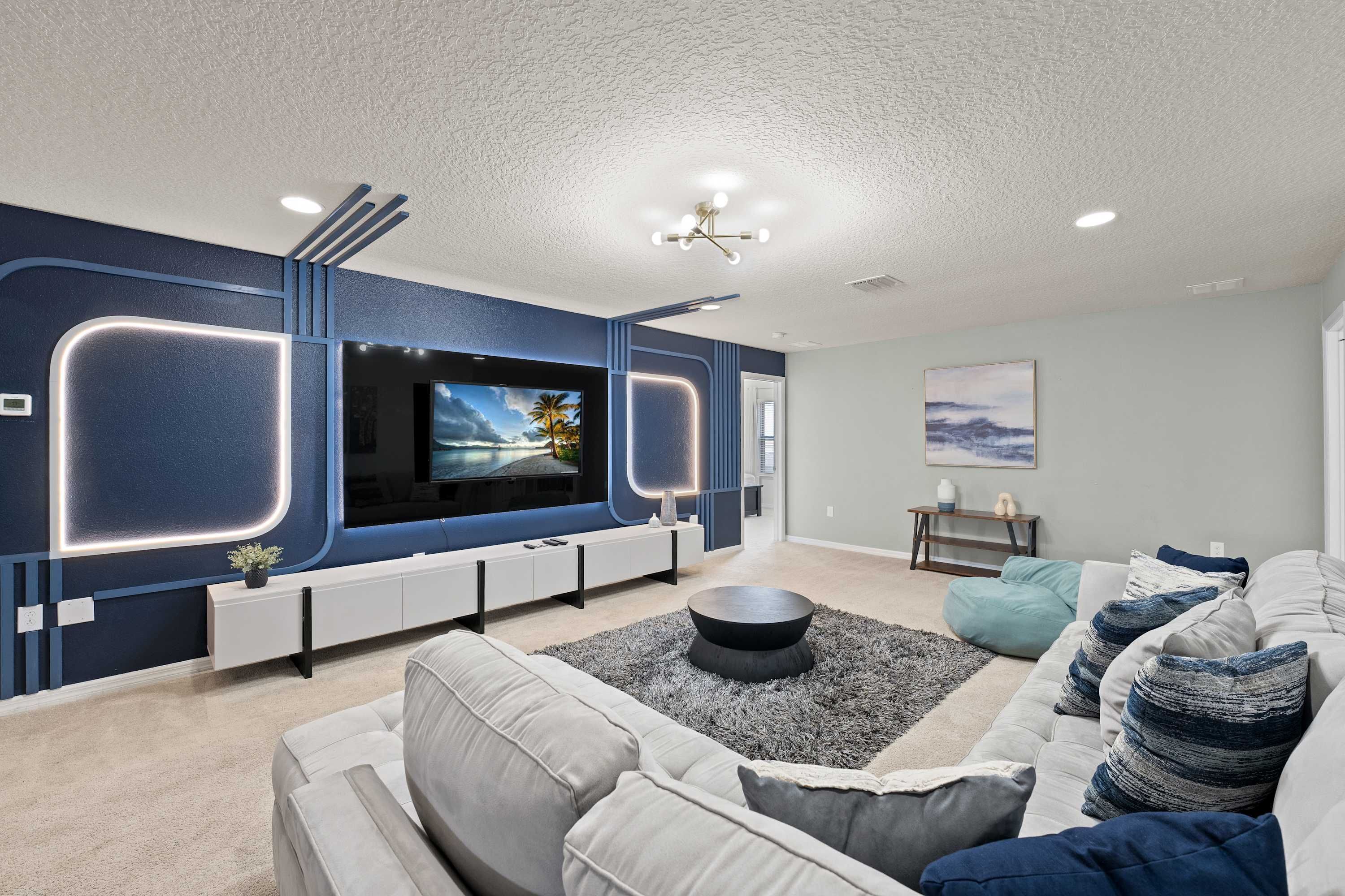 A modern living room with a flat-screen TV, a sofa, a coffee table, and a decorative rug.