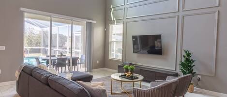 A modern living room with a grey sofa, a coffee table, and a TV mounted on the wall.