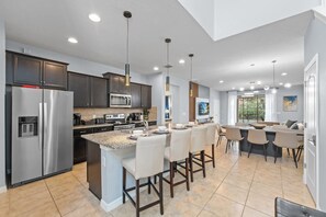 A modern kitchen with a central island, stainless steel appliances, and pendant lighting. - Ultimate 6BR Fun Pool Table Movie Games (Kissimmee)