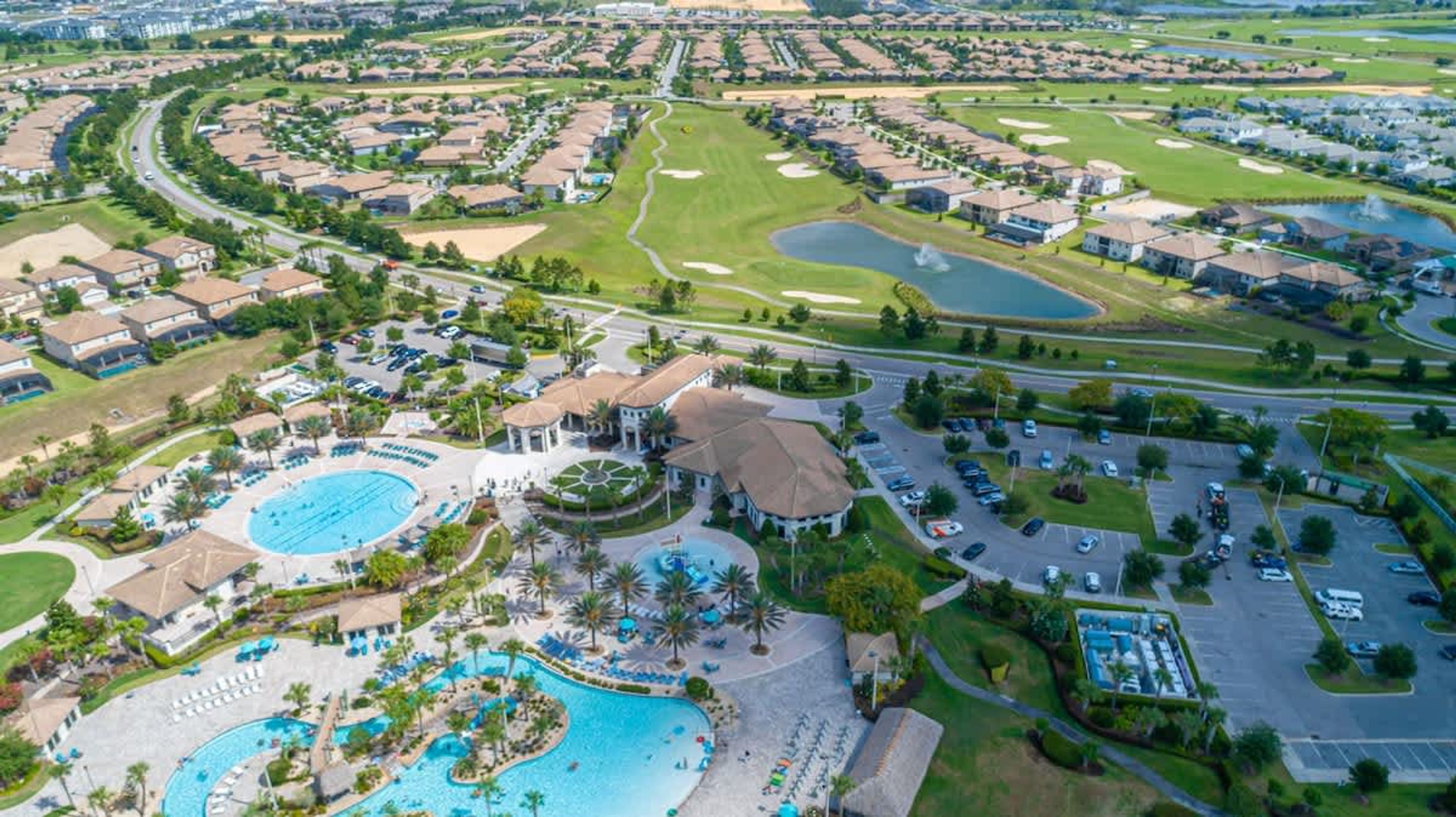 An aerial view of a golf resort with multiple pools, a pavilion, and residential areas.
