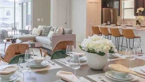 A dining area with a table set for four, a sofa, and a kitchen in the background. - Toy Story Villa - 5BD Game Room Pool Spa Near Disney (Davenport)