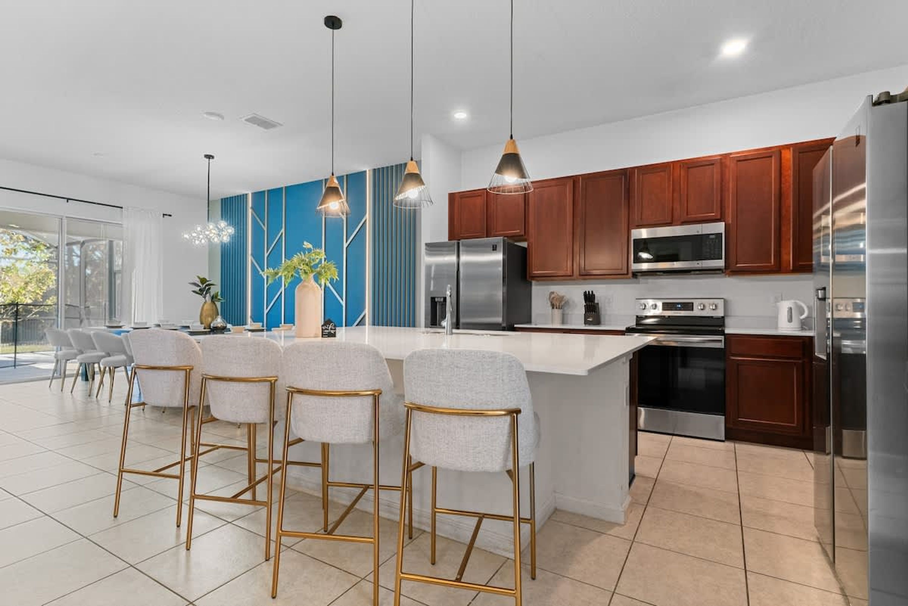 A modern kitchen with a central island, bar stools, stainless steel appliances, and wooden cabinets.