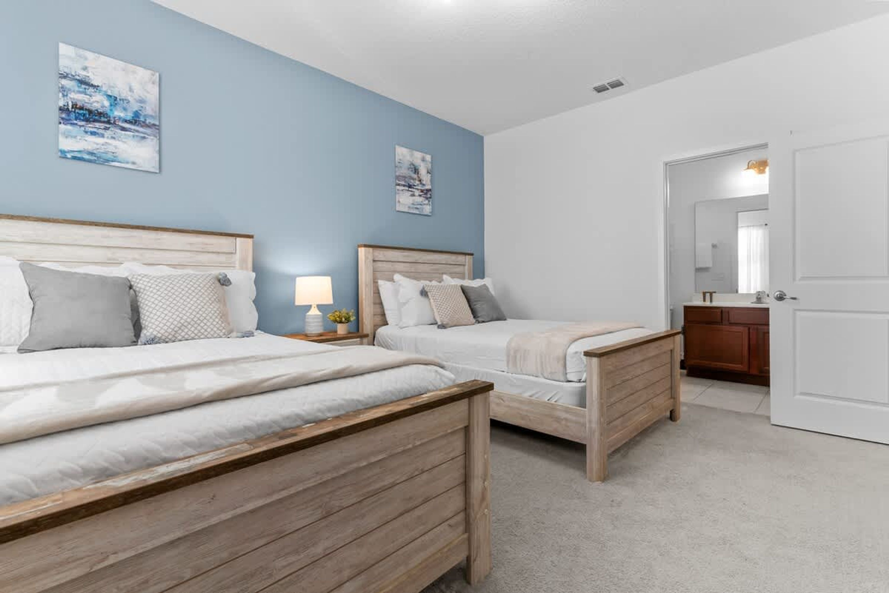 A bedroom with two wooden beds, a nightstand with a lamp, and a dresser.