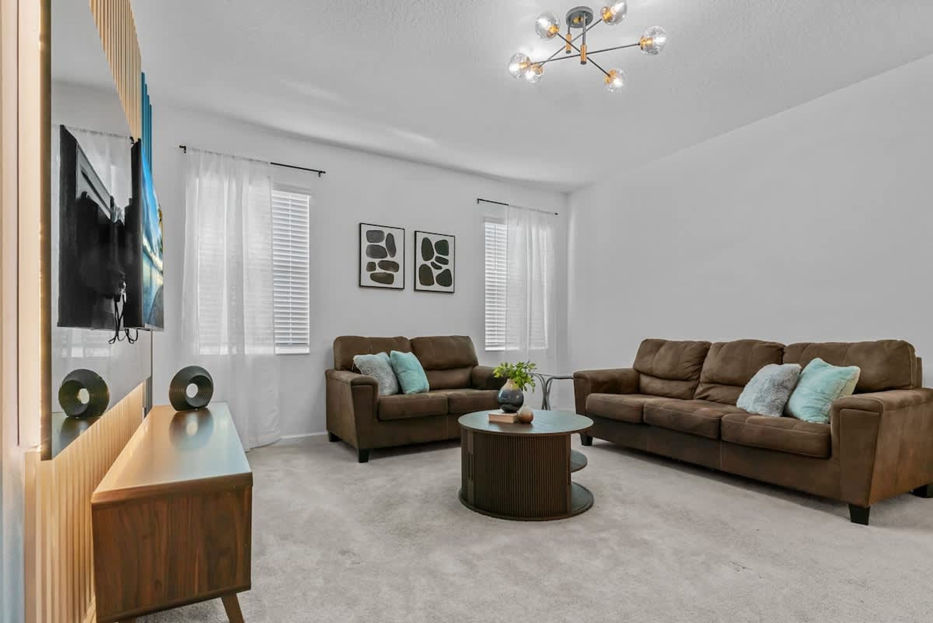 A modern living room with two brown sofas, a wooden coffee table, and a TV on a stand.