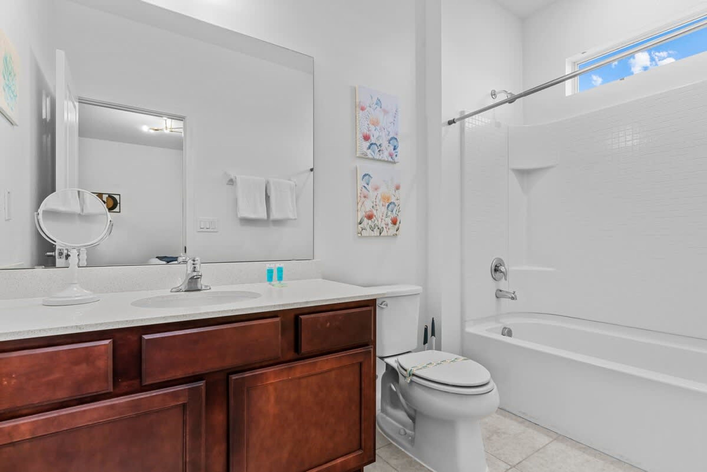 Une salle de bain moderne avec un grand miroir, deux lavabos, des toilettes et une baignoire.