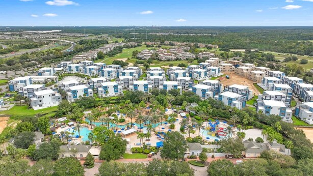 A resort with multiple buildings, a central pool area, and surrounding greenery. - Resort-style 4-bed Loft Condo (Kissimmee)