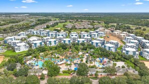 Un complex turístic amb diversos edificis, una zona de piscina central i vegetació als voltants.