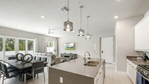 A modern kitchen with a central island, stainless steel appliances, and pendant lighting. - Resort-style 4-bed Loft Condo (Kissimmee)