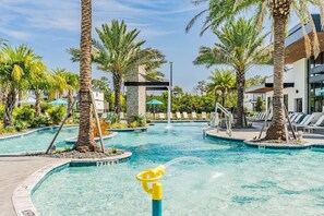 Ein Pool mit Palmen und Liegestühlen, umgeben von Gebäuden.