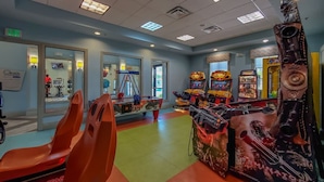 Une salle équipée de jeux d’arcade, de matériel de musculation et d’un mur recouvert de miroirs.
