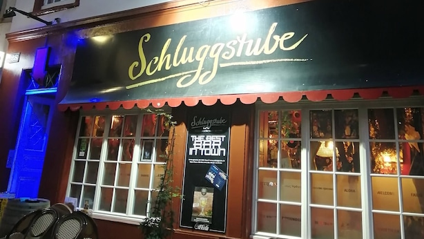 A building with a sign reading "VAT69 Finest Scotch Whisky" and another sign "Schluggstube" with a Coca-Cola advertisement. - Room-studio D on Barfüsserplatz Central (Basel)