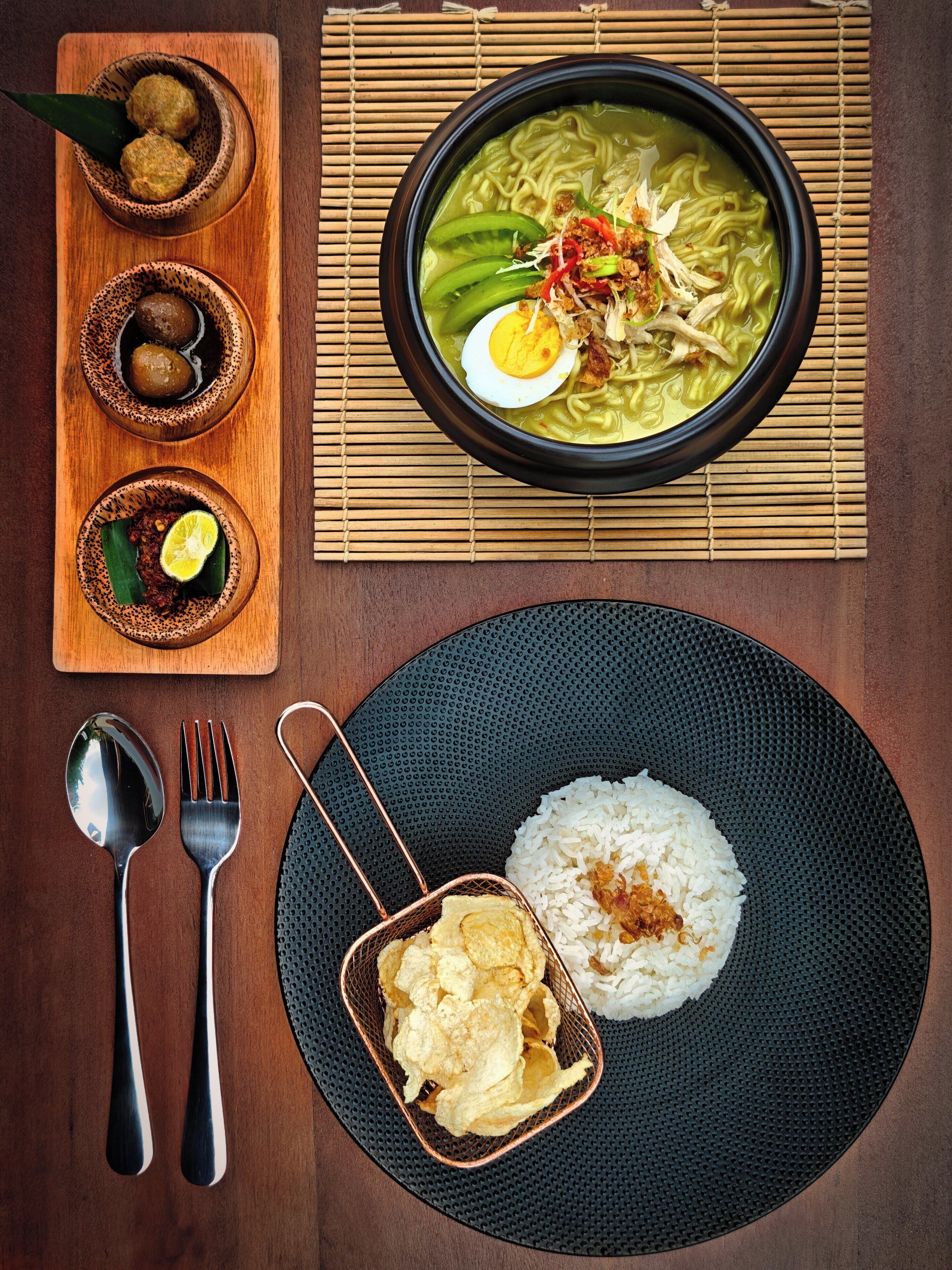 Un repas composé de riz, d’un bol de soupe et de trois petits bols d’accompagnements, le tout servi sur une table en bois.