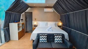 A modern bedroom with a large bed, a sofa, a wooden table, and a skylight.
