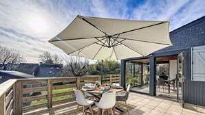 Un patio con una mesa dispuesta para cuatro personas, rodeado de sillas y cubierto por una sombrilla grande.