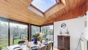 Un comedor con una mesa dispuesta para cuatro, techo de madera y vistas al jardín a través de amplios ventanales.