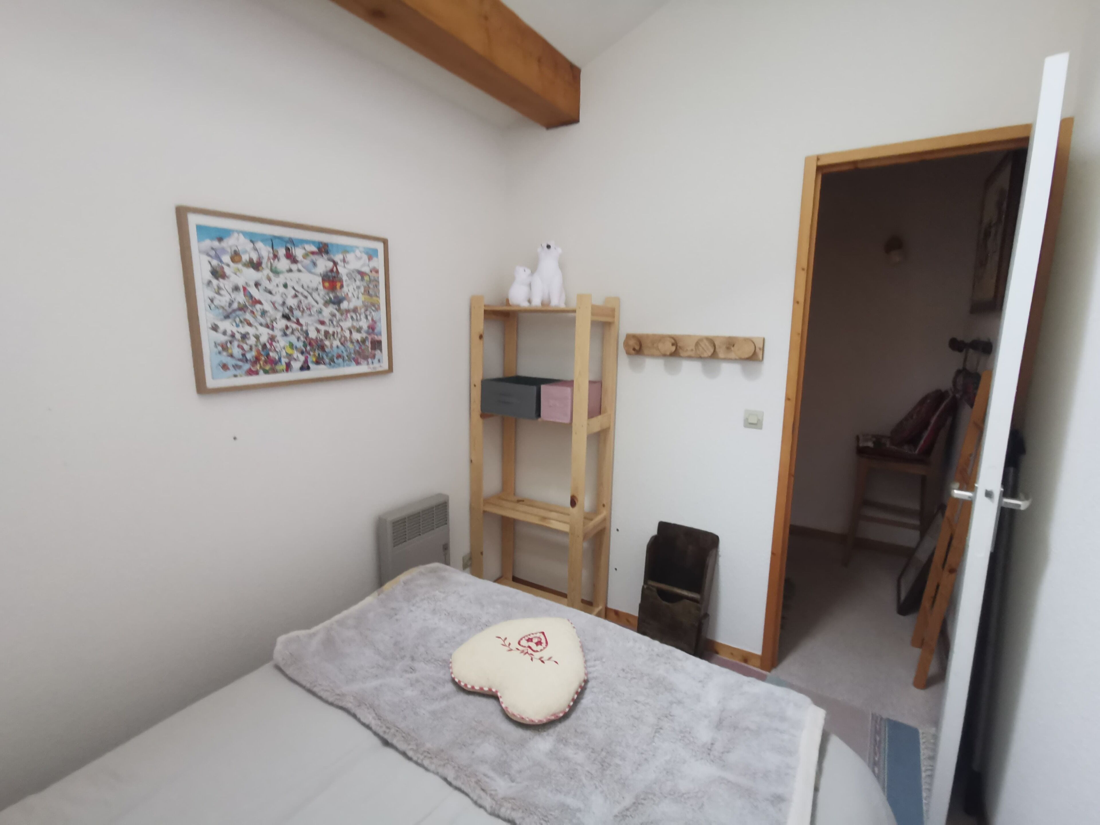 A bedroom with a bed, a wooden shelf unit, a whiteboard, and a painting on the wall.