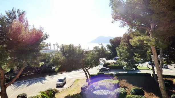 A parking lot with a car, surrounded by trees and a view of a body of water. - Apartment in Pin Rolland by Ste Asile Beach (Saint-Mandrier-sur-Mer)