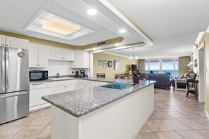 A modern kitchen with white cabinets, a granite countertop, and a built-in microwave. - Shoreline Towers 1043 2 Bedroom Condo (Destin)