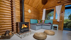 Interior d'una cabana de fusta amb una llar de foc, un sofà i una taula petita.
