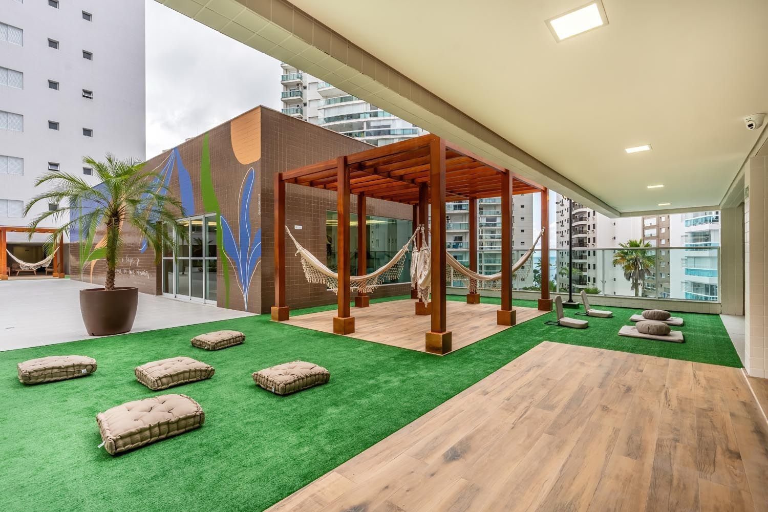 A rooftop terrace with a wooden pergola, hammocks, and artificial grass.