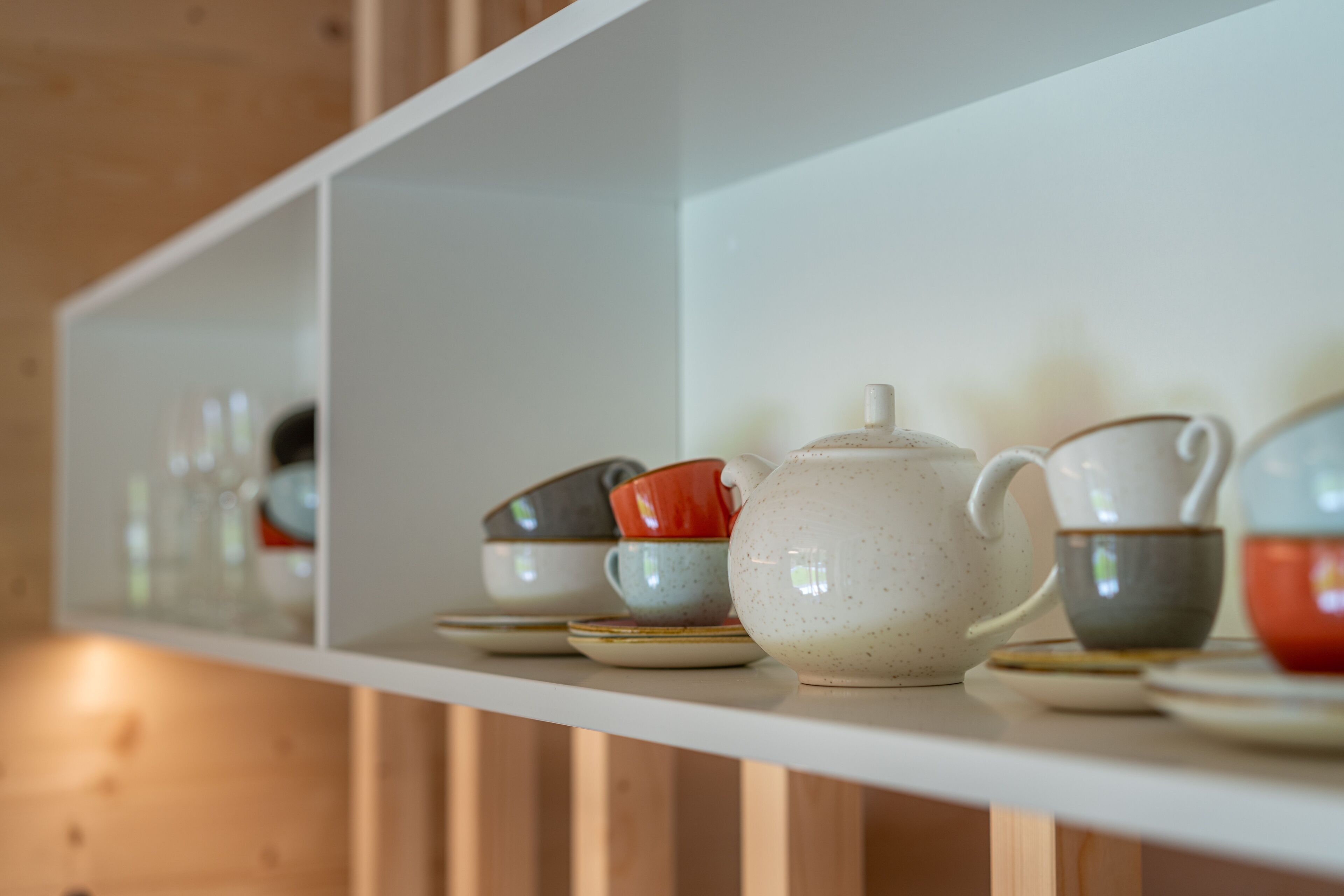 A shelf with various ceramic tea cups and a teapot.