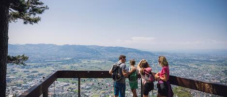 A group of people standing on a viewing platform with a panoramic view of a city and mountains.