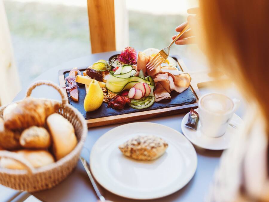 A breakfast buffet with various pastries, fruits, and a coffee cup.