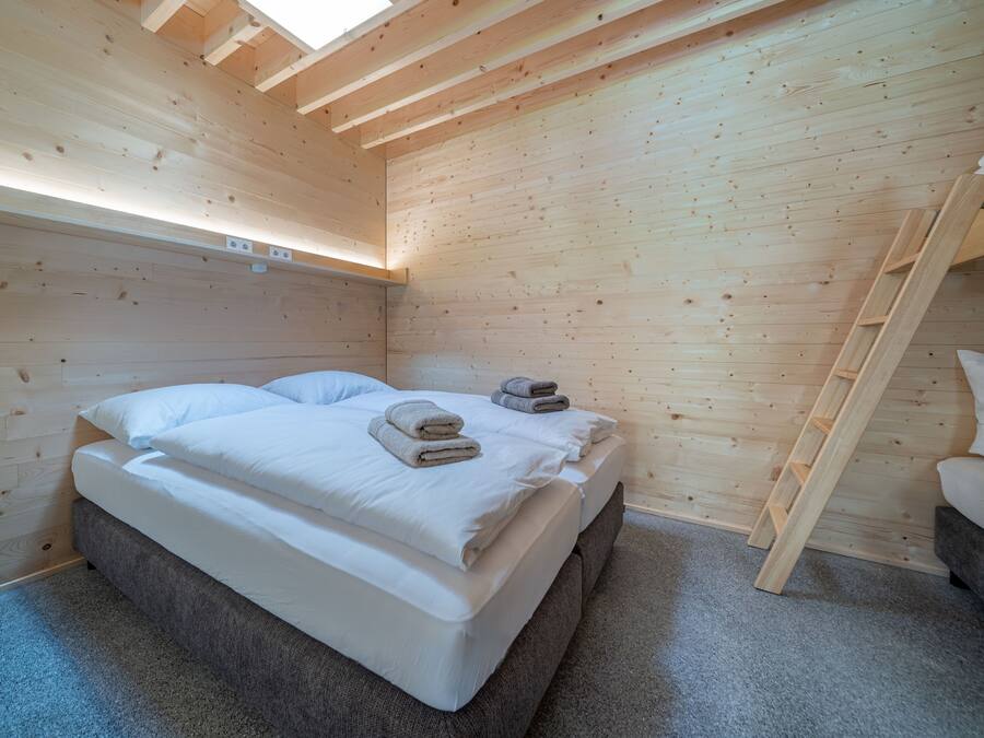 Una habitación de madera con una cama, un sofá y una escalera.