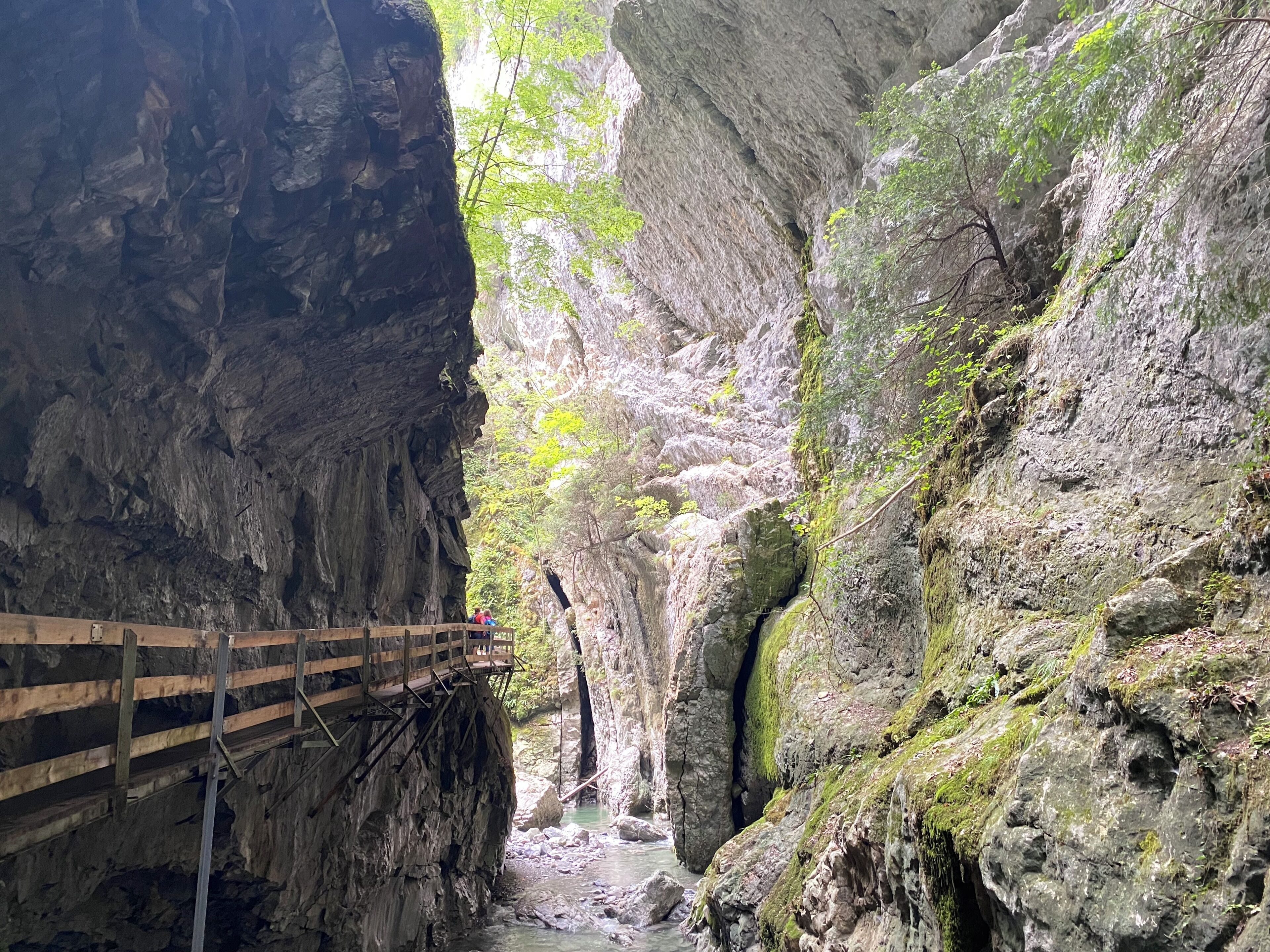 A wooden walkway over a river in a rocky gorge.