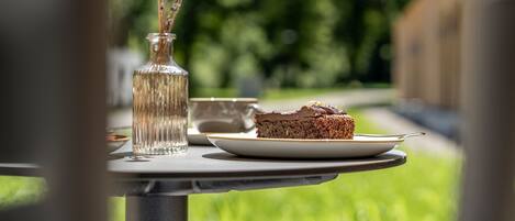 A table with a glass vase, a plate with a slice of cake, and a cup.