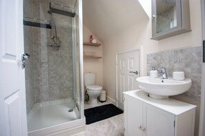 Een aparte badkuip en douche, een diep bad, een haardroger, handdoeken