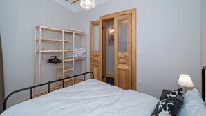Un dormitorio con una cama, un armario de madera, un estante y una lámpara colgante.