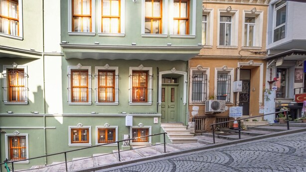 Un edificio de varios pisos con una puerta verde y numerosas ventanas.