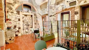 A stone-walled courtyard with a tiled floor, a round table, and chairs. - Il Cortiletto di Ortigia - Two-room apartment (Siracusa)