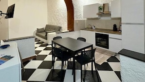 A compact kitchen with a dining area, featuring a checkered floor, a sofa, and a small table with chairs. - Il Cortiletto di Ortigia - Two-room apartment (Siracusa)