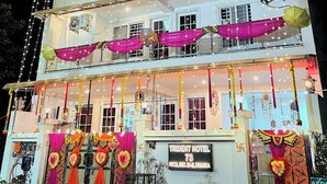 A multi-story hotel with balconies, string lights, and colorful drapes. - Hotel Trident Dwarka (New Delhi)