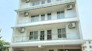 A multi-story building with balconies, air conditioning units, and a sign indicating it is the Trident Hotel. - Hotel Trident Dwarka (New Delhi)