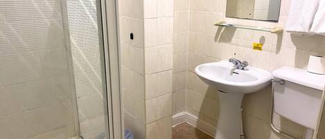 Une salle de bain avec une douche à parois de verre, un lavabo sur colonne et des toilettes.