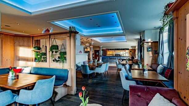 Un interior moderno con paneles de madera, asientos azules y una zona de comedor central.