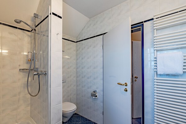 Un baño con ducha, inodoro y perchero.