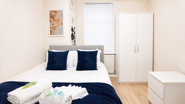 A hotel room with a bed, a wardrobe, and a small bedside table. - Stunning 3-Bed House in the Heart of Newport, Sleeps 7 (Newport)