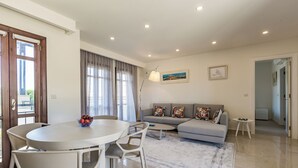 Een moderne woonkamer met een grijze bank, een ronde eettafel en een salontafel.