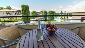 Een balkon met een tafel, een fles en een schaal fruit.
