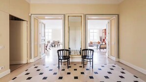 A spacious living room with a large mirror, two black chairs, and a patterned floor. - JUST STEPS AWAY FROM THE MONNAIE MUSEUM, SEINE RIVER & PONT NEUF – SAINT GERMAIN (Paris)